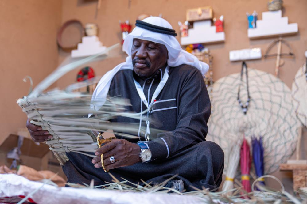 رجل جالس يعمل بسعف النخيل (الخوص).